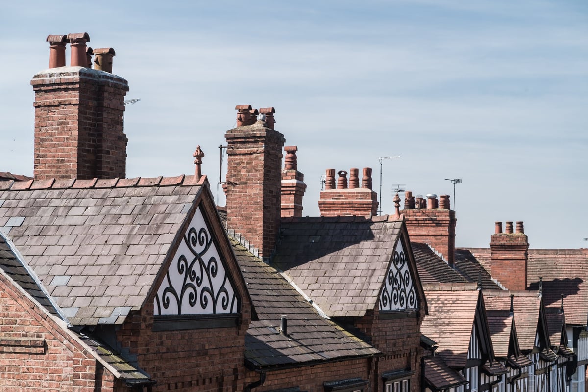 Row of terraced house chimneys against a blue cloudy sky in Chester, England